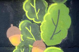 Fragment von Graffiti-Zeichnungen. Die alte Wand ist mit Farbflecken im Stil der Straßenkunstkultur dekoriert. Eichenlaub und Eicheln foto