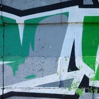 Fragment von Graffiti-Zeichnungen. Die alte Wand ist mit Farbflecken im Stil der Straßenkunstkultur dekoriert. farbige Hintergrundtextur in Grüntönen foto