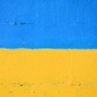 Fragment von Graffiti-Zeichnungen. Die alte Wand ist mit Farbflecken im Stil der Straßenkunstkultur dekoriert. ukrainische Flagge foto