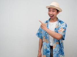 Fröhlicher tourismus asiatischer mann trägt hut lächeln und zeigt mit dem finger auf den kopienraum foto