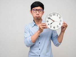 asiatische mannbrille, die auf die uhr in der hand schaut, fühlt sich gelangweilt bei der arbeit foto