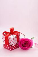 Geschenkbox mit rosa Rose im Hintergrund. vertikal. geburtstag, 14. februar, internationaler frauentag, muttertag und 8. märz. kopierraum foto