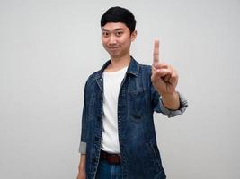 positive asiatische mann jeanshemd geste zeigen einen finger nach oben isoliert foto