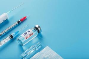 eine Reihe von Ampullen und Spritzen mit der Aufschrift Virusimpfstoff und eine Reihe von Spritzen auf blauem Hintergrund.