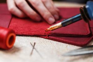 Ein Lederhandwerker arbeitet mit Leder. näht Lederwaren. Dinge in Handarbeit machen. foto