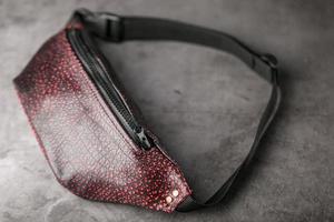 Tasche am Gürtel aus strukturiertem Leder in Bordeaux-Farbe, Banane auf grauem Hintergrund. foto