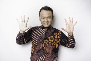 Aufgeregter indonesischer Mann, der ein Batikhemd trägt und die Nummer 12345 per Handgeste gibt foto