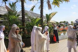 eine gruppe von frauen in weißen kleidern, die herumlaufen und den celosia-blumengarten in semarang genießen foto