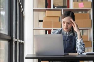 Teenager asiatisches Mädchen Freiberufler Kleinunternehmen ernstes Arbeiten zu Hause im Büro mit Laptop-Verpackungslieferung Online-Markt bei Bestellungen an Kunden und Verkaufsausfall foto