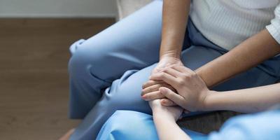 Der glückliche Patient hält die Pflegekraft für eine Hand, während er Zeit miteinander verbringt. ältere frau im pflegeheim und krankenschwester. foto