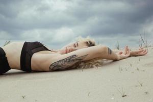attraktive junge im schwarzen bh auf szenischer fotografie des strandes foto