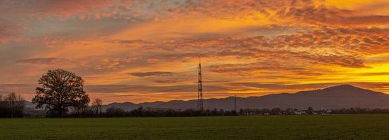 Bild eines farbenfrohen und kontrastreichen Sonnenaufgangs mit hellen Wolkenformationen und Konturen von Strommasten foto