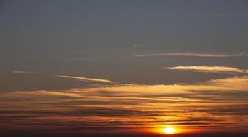 Bild eines dramatischen und farbenfrohen Himmels mit Sonne während des Sonnenuntergangs foto