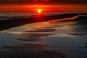 Muster im Meeressand bei Sonnenuntergang foto