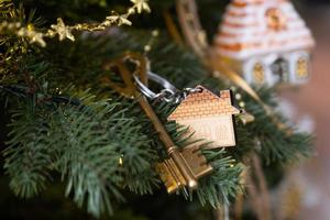 schlüssel zum haus mit einem schlüsselbund hängt am weihnachtsbaum. ein geschenk für neujahr, weihnachten. Bau, Design, Projekt, Umzug in ein neues Haus, Hypothek, Miete und Kauf von Immobilien. Platz kopieren foto