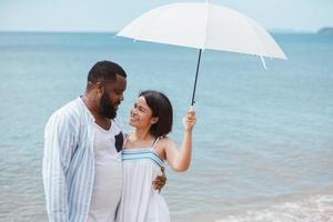 Liebesmoment des Paares, das zusammen lacht und Spaß hat, während es am Strand spazieren geht foto