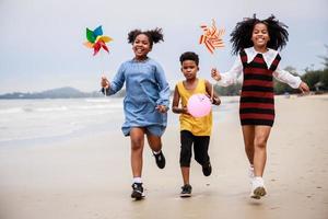 glückliche gruppe von afroamerikanischen kindern windturbinenspielzeug am strand foto