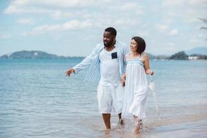 amerikanisches afrikanisches paar, das zusammen spaß hat, während es am strand spazieren geht foto