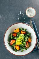 Draufsicht auf gesunden veganen Salat mit Tomaten, Rucola, Avocado und Sesam. Keto-Diät-Menü. Ansicht von oben foto