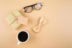 glücklicher vatertagshintergrund. geschenkbox, brille, schmetterling, tasse kaffee im hintergrund. foto