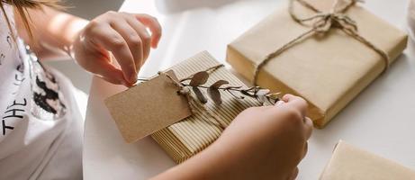 weibliche hände packen geschenkdekor mit eukalyptus und notizwagen für text. Zero-Waste-Weihnachten foto