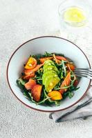 vertikaler schuss von rucola, lachs, avocado, tomatensalat. gesund essen, leben. Ansicht von oben, vertikal foto