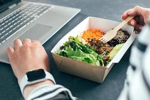 Frau beim Mittagessen in recycelter Schüssel mit Laptop. lebensmittellieferung, quarantäne, essenskonzept herausnehmen foto