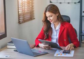 marketing, finanzen, buchhaltung, planung, geschäftsfrauen analysieren unternehmensergebnisse und gewinne mit grafikstatistiken. Verwenden Sie einen Laptop-Computer und einen Taschenrechner, um den Saldo des Unternehmens zu berechnen. foto