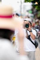 Professioneller asiatischer Kameramann konzentriert sich mit seiner spiegellosen Kamera neben dem Straßenfeld auf das Bild. foto