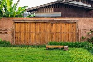 die ziegelmauer, die zaunbarriere ist mit einem loch auf der wand im asiatischen stil mit gartengrasfeld im vordergrund gestaltet foto