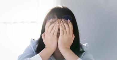 Brille asiatisch thailändisch - chinesische Frau ist schüchtern und weint Gesicht hinter ihrer Hand. scheues Konzept. foto