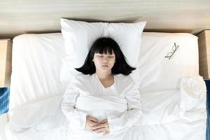 asiatische frau schläft auf weißem bett, nachdem sie den ganzen tag erschöpft und versucht hat. foto