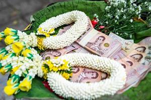 thailändische banknote 1000 baht in phan-tablett mit podest mit graland, um auf traditionelle thailändische weise verdienste zu verdienen und geld für wohltätige zwecke zu spenden. foto