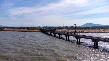 luftaufnahme eines erstaunlichen reisezuges, der auf einer schwimmenden eisenbahnbrücke über dem wasser des sees in pa sak jolasid dam mit blauem himmel in lopburi, thailand, geparkt ist. foto