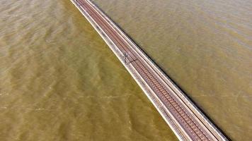 luftaufnahme eines erstaunlichen reisezuges, der auf einer schwimmenden eisenbahnbrücke über dem wasser des sees in pa sak jolasid dam mit blauem himmel in lopburi, thailand, geparkt ist. foto