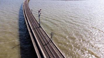 luftaufnahme eines erstaunlichen reisezuges, der auf einer schwimmenden eisenbahnbrücke über dem wasser des sees in pa sak jolasid dam mit blauem himmel in lopburi, thailand, geparkt ist. foto