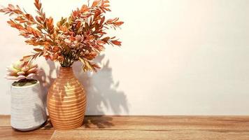 Zierpflanzen in einer Holzvase und kleine kleine Pflanzen in einer Keramikvase auf Holzregalen und grauem Mörtelwandhintergrund und weißem Wandhintergrund mit gelben Downlights und Platz für Texte. foto