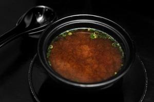 würzige chinesische Suppe auf schwarzem Hintergrund foto