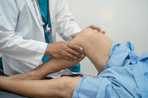 asiatischer Arzt Physiotherapeut untersucht, massiert und behandelt Knie und Bein eines älteren Patienten im Krankenschwesterkrankenhaus der orthopädischen Klinik. foto