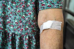 Asiatische Senioren oder ältere Frauenpatienten zeigen Watte aufhören zu bluten, nach Blutentnahmetests für die jährliche körperliche Gesundheitsprüfung, um Cholesterin, Blutdruck und Zuckerspiegel zu überprüfen foto