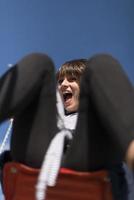 Eine infantile und glückliche Frau, die auf einer Kinderrutsche auf einem Spielplatz sitzt foto