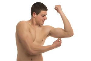 Ein fitter junger Mann, der Körperfett auf seinen Körper drückt foto