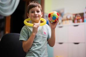Junge trug im Kinderzimmer einen Schlauch am Hals mit Ball in der Hand. foto