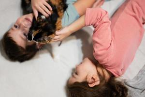 bruder und schwester mit kitty cat liegen auf dem sofa. Kinderliebe für Haustiere. foto