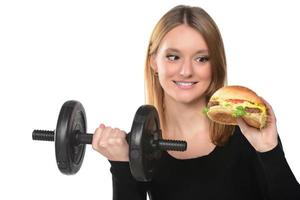 Frau hebt Gewichte und isst ein Sandwich foto