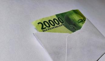 indonesische rupiah-banknoten im wert von idr 20.000 in einem weißen umschlag isoliert auf weißem hintergrund foto