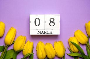8. März-Banner. Kalender mit Datum liegt umgeben von gelben Tulpen foto
