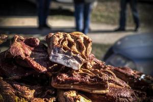 ein Stand im Freien, an dem Speckstücke und Trockenfleisch verkauft werden foto