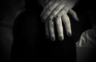 Eine Nahaufnahme von weiblichen Händen, die auf einem Schoß in Schwarz und Weiß gekreuzt sind foto
