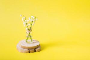 Maiglöckchenstrauß in einem Miniaturglas auf gelbem Hintergrund mit Kopierraum. muttertag leere grußkarte foto